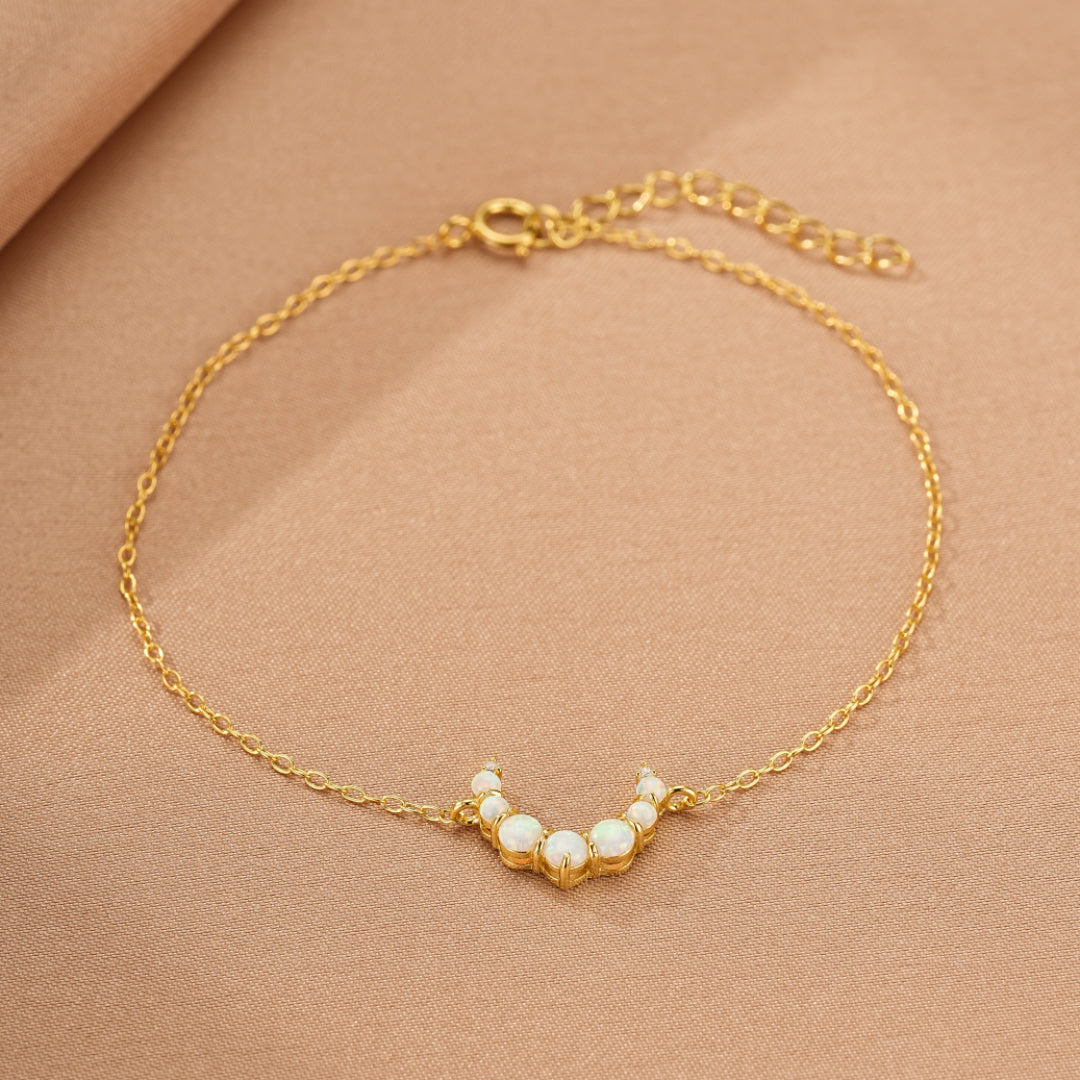 Bracelet fin en argent 925 plaqué or 18K avec un pendentif en forme de croissant de lune orné de petites pierres d'opale blanches.