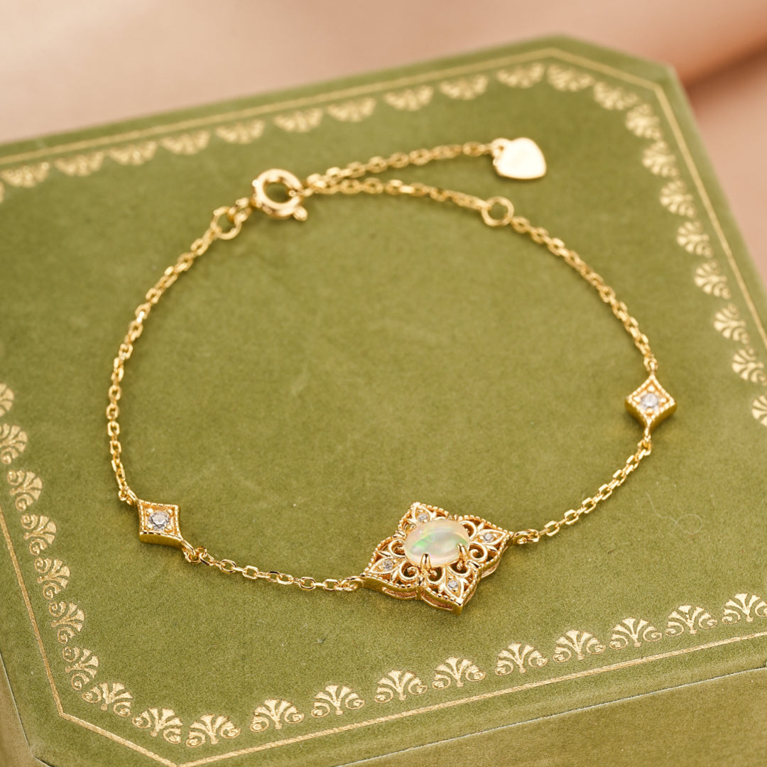 Bracelet fin en argent plaqué or 10K, orné d'une opale centrale entourée de petits diamants, avec des motifs géométriques et un petit cœur à l'attache.