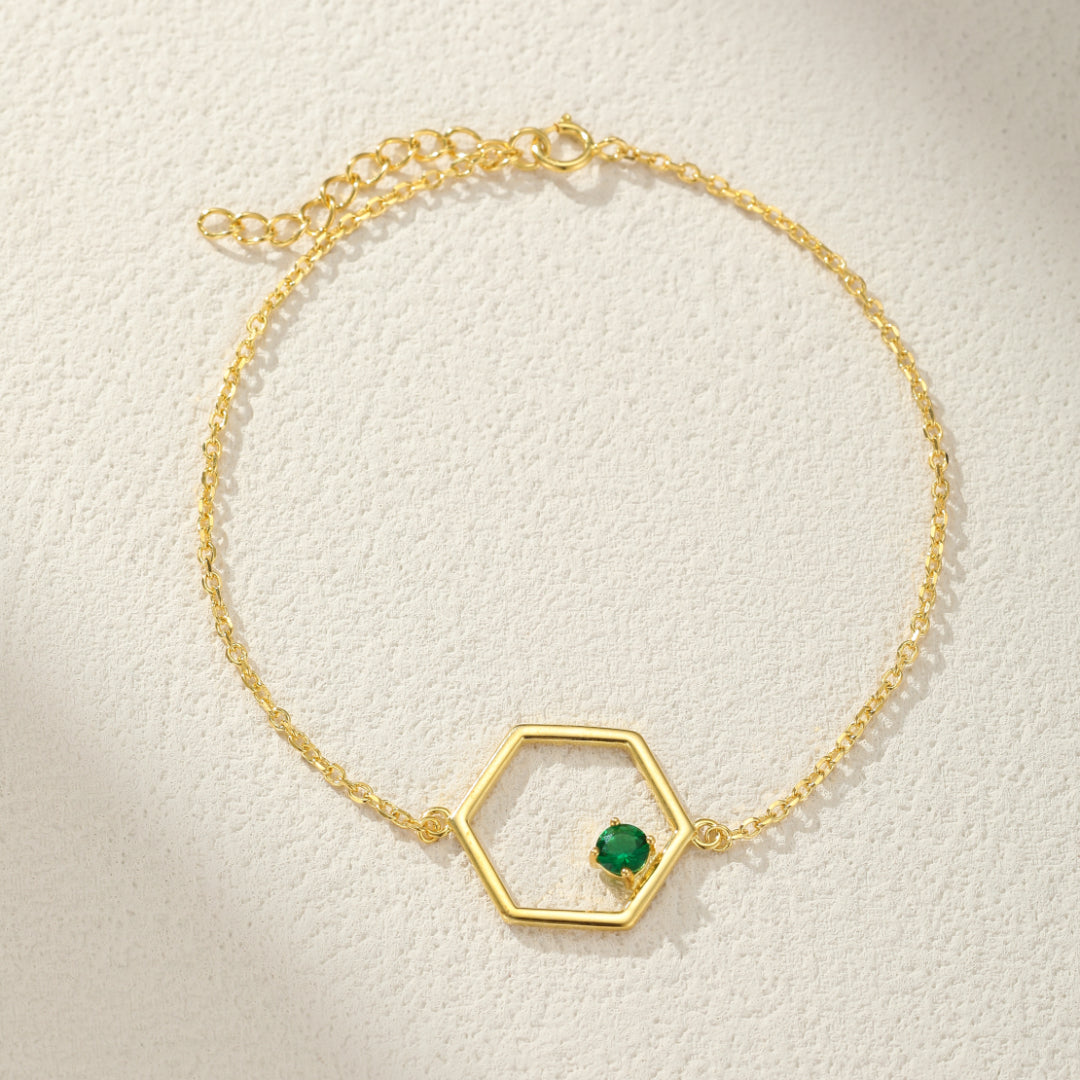Bracelet en argent plaqué or avec un pendentif hexagone et une petite pierre verte au centre.