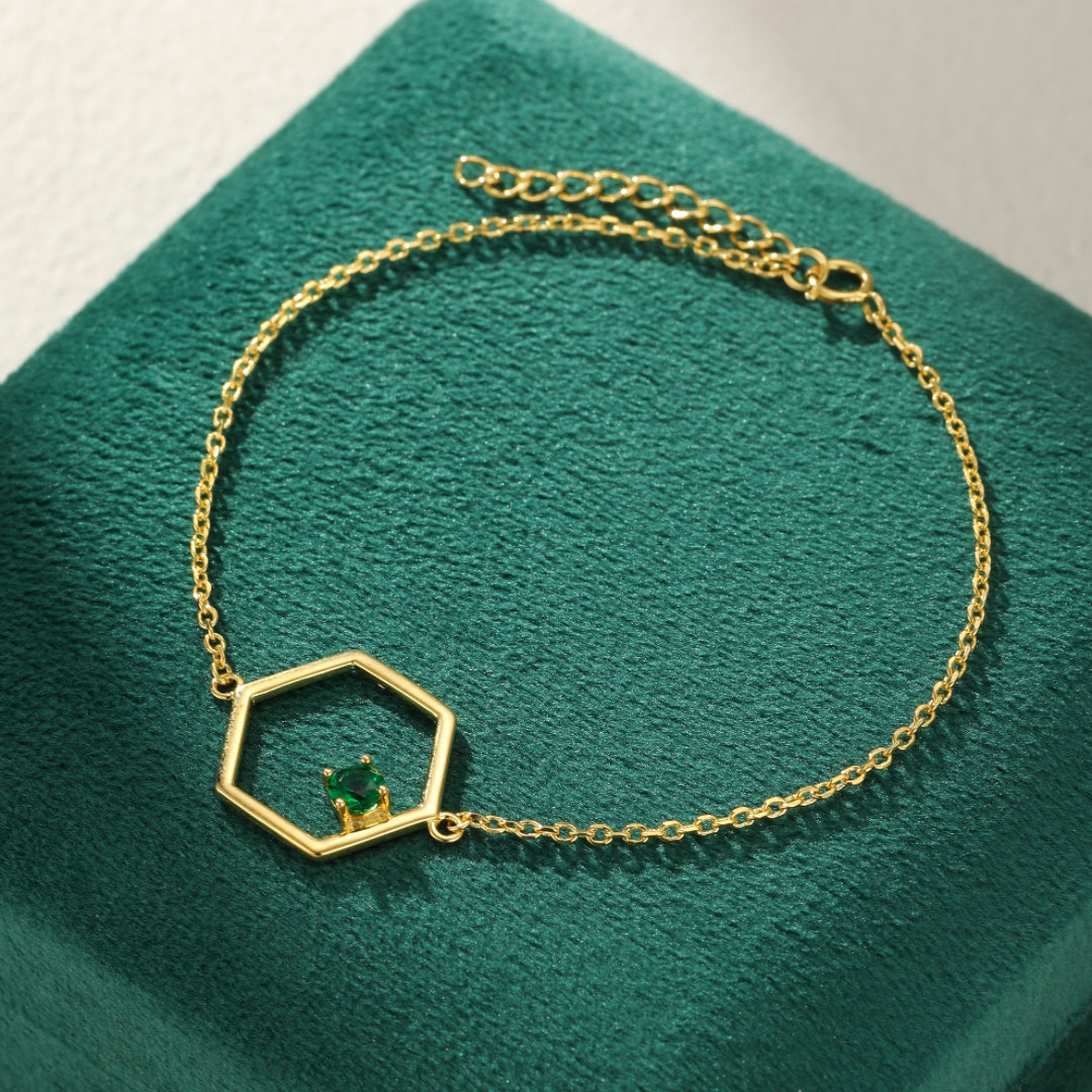 Bracelet en argent plaqué or avec un pendentif hexagone renfermant une pierre de péridot verte.