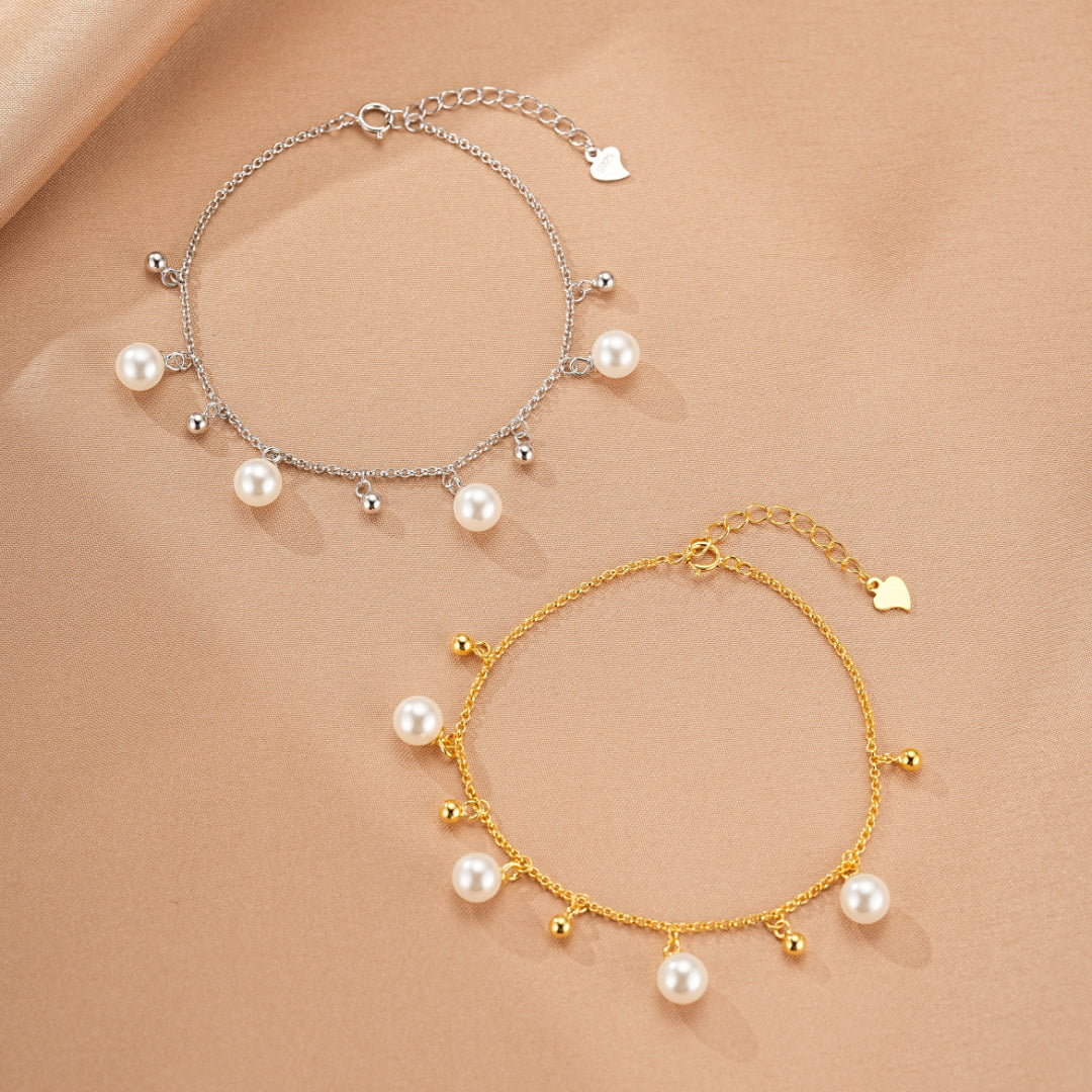 Deux bracelets fins, l'un en argent 925 et l'autre doré, ornés de petites perles et de breloques sphériques, avec un petit cœur à l'extrémité de la chaîne.