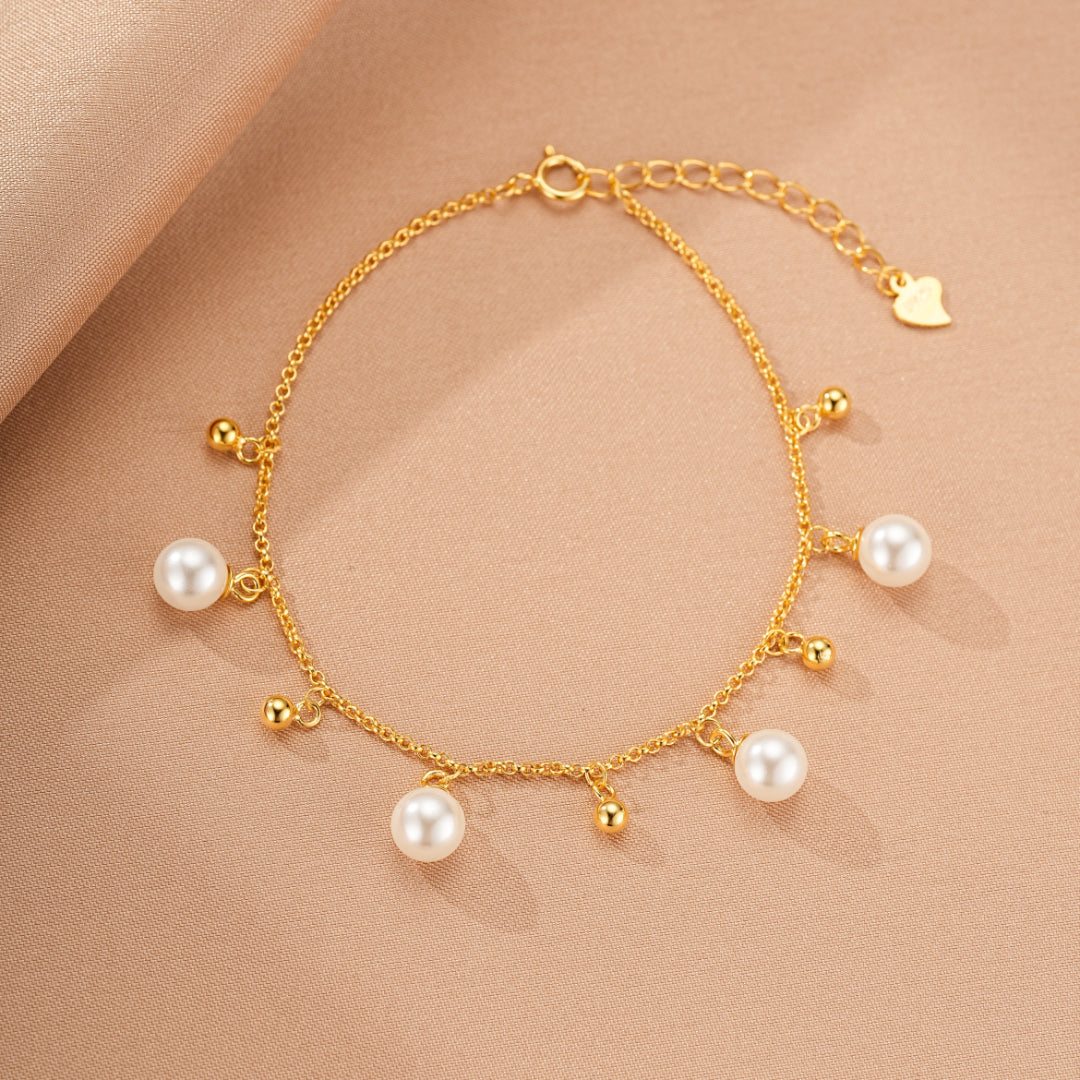 Bracelet en argent 925 plaqué or, orné de perles blanches et de petites billes dorées, avec un fermoir ajustable et un pendentif en forme de cœur.