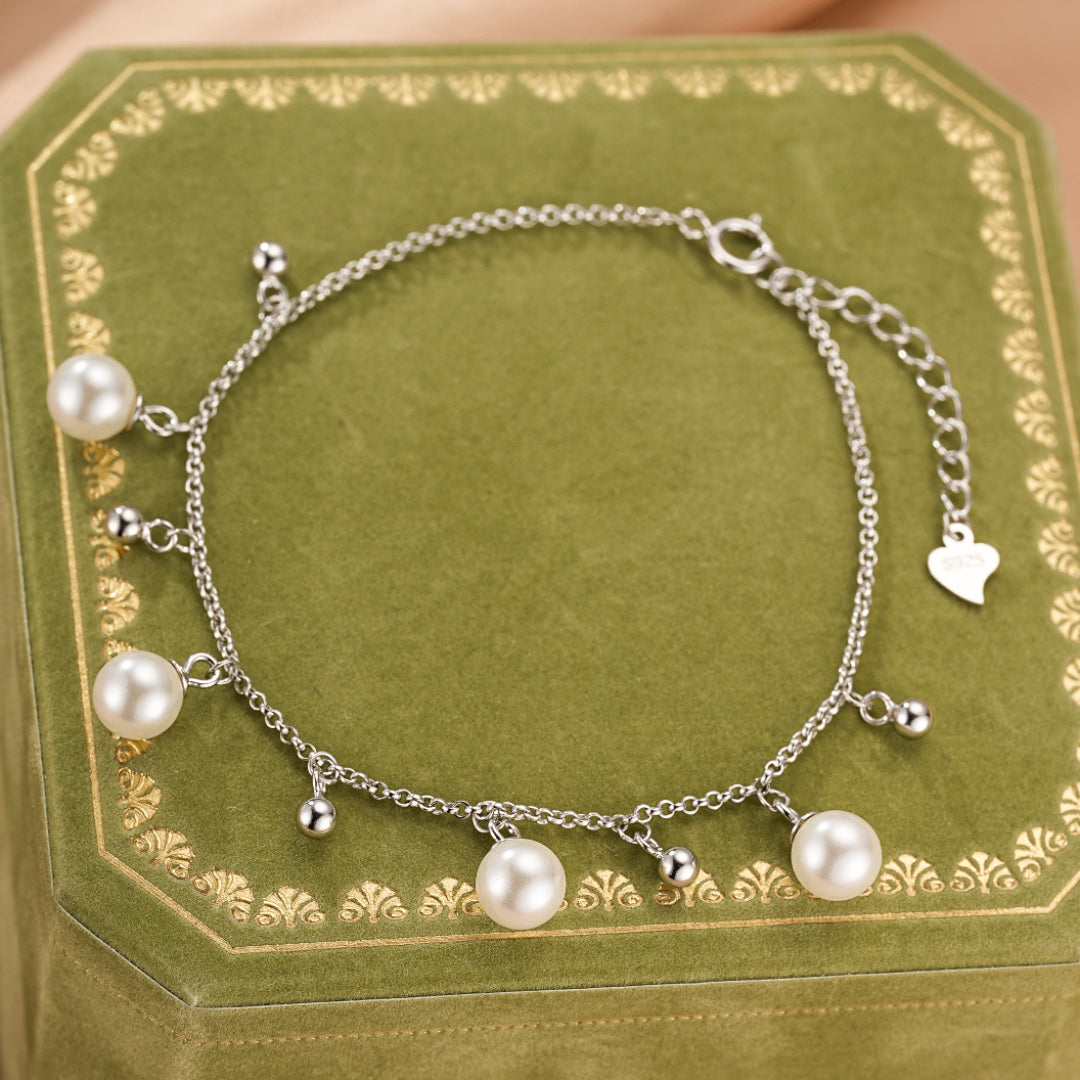 Bracelet en argent 925 avec plusieurs perles blanches et de petites billes argentées suspendues à une chaîne délicate.