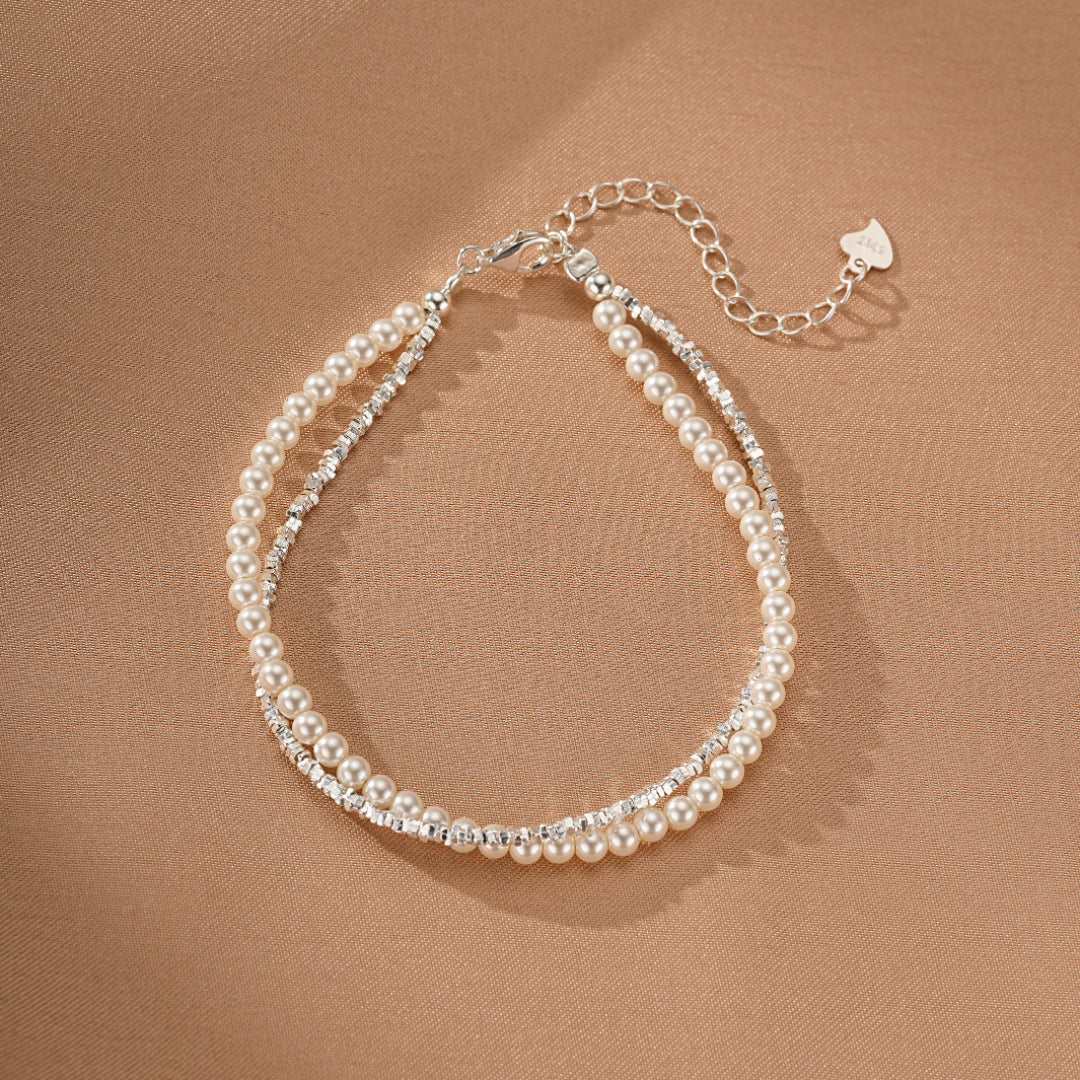 Bracelet double rangs en argent orné de perles nacrées et de cristaux scintillants, avec fermoir mousqueton et chaînette d'extension.