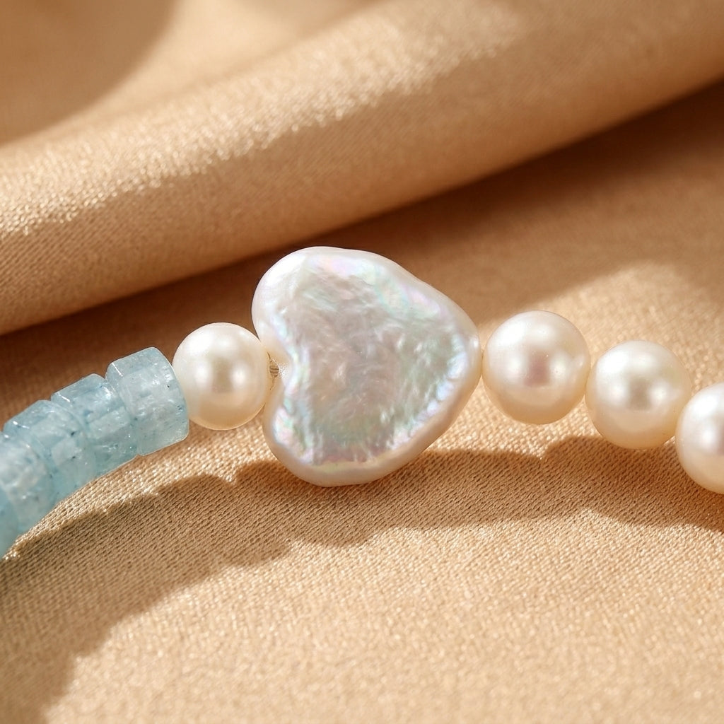 Bracelet "Lien Paisible" avec perles blanches, une perle centrale en forme de cœur et des pierres d'aigue-marine bleues, en argent.