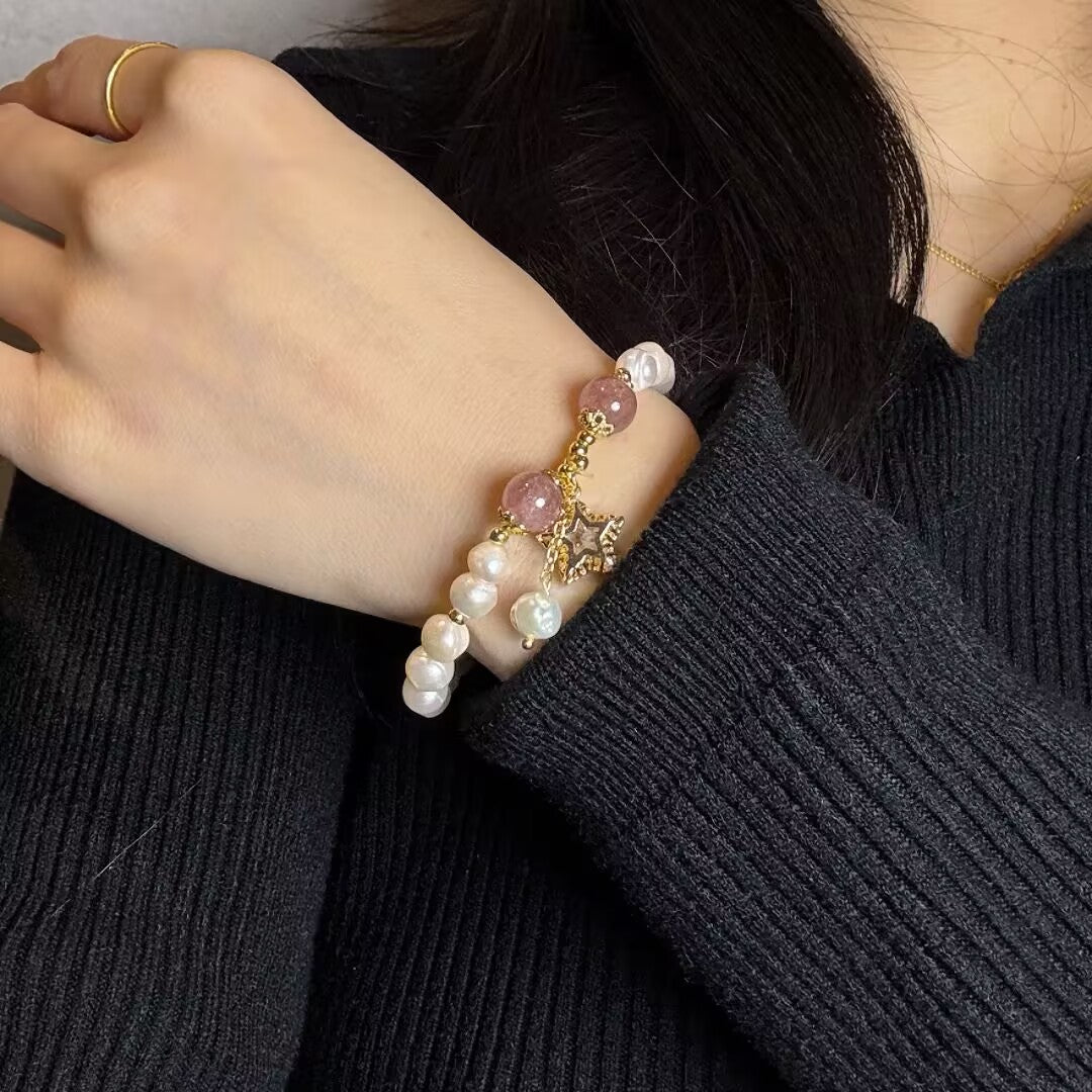 Bracelet bohème avec perles nacrées, perles de quartz fraise roses et un pendentif étoile filante, porté au poignet d'une femme.