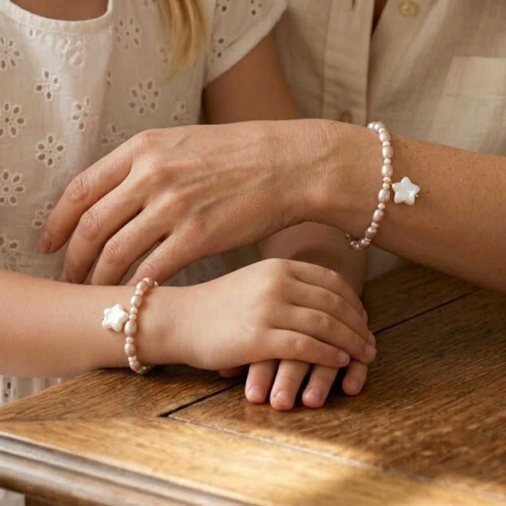 Bracelet pour enfant et adulte en perles roses et blanches avec un pendentif étoile.