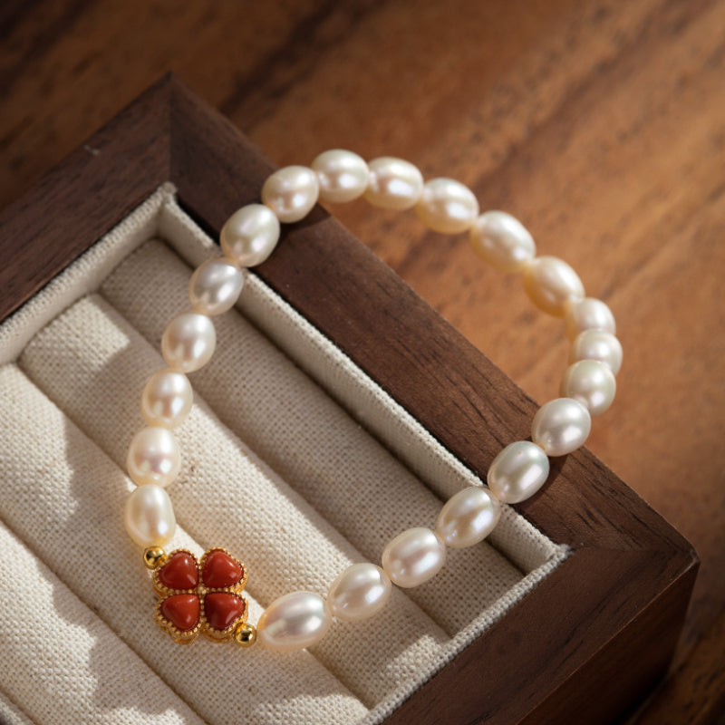 Bracelet en perles d'eau douce avec un charmant trèfle en corail rouge et un fermoir plaqué or.