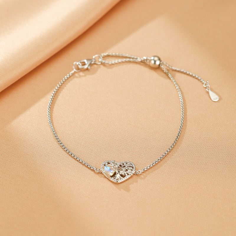 Bracelet en argent avec un pendentif en forme de cœur ajouré orné d'une pierre de lune et d'un motif d'arbre de vie.