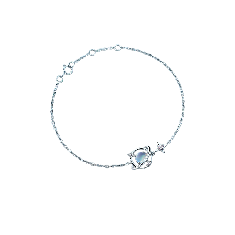 Bracelet fin en argent 925 avec un pendentif représentant une planète ornée d'une pierre de lune et d'une étoile scintillante, avec des petits cristaux autour.