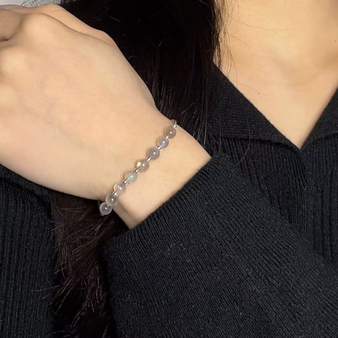 Bracelet fin en pierres de lune naturelles et perles d'argent, porté au poignet d'une femme.