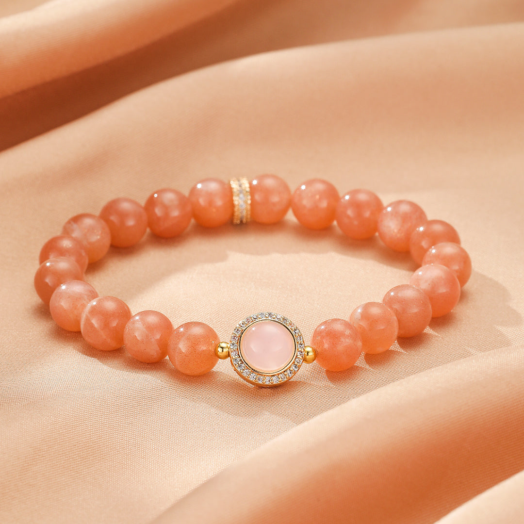 Bracelet Aura Tendre fait de perles de pierre de soleil pêche et d'un pendentif central en quartz rose entouré de cristaux étincelants.