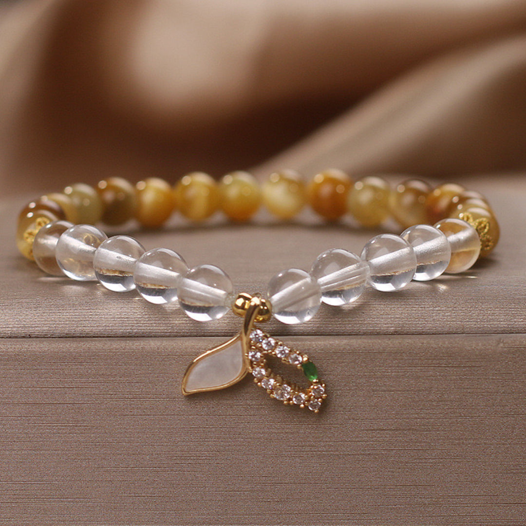 Bracelet fait de perles de quartz clair et d'œil de tigre, orné d'un pendentif en forme de feuille orné de cristaux et d'une petite pierre verte.