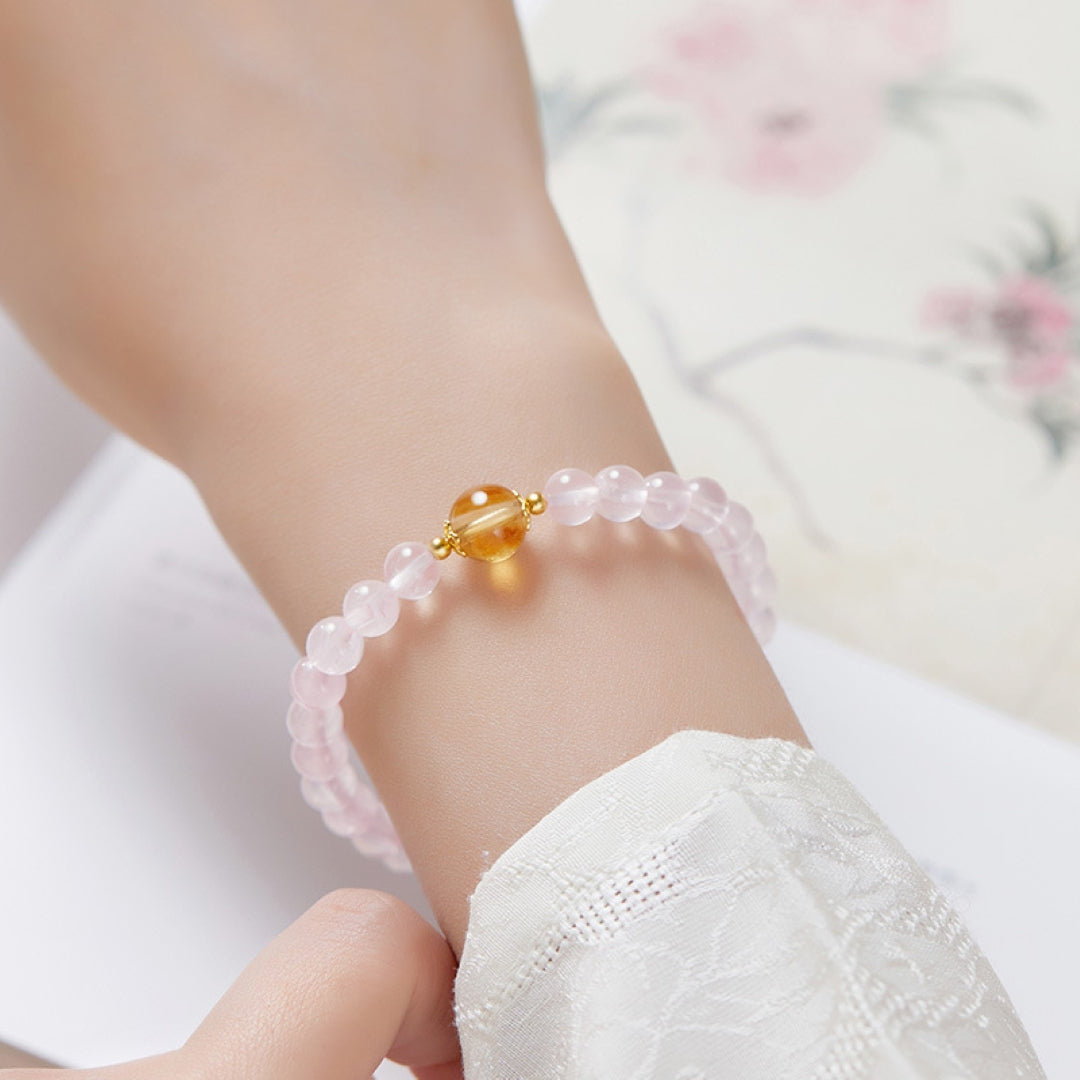Bracelet Équilibre Radieux avec des perles rondes en quartz rose et une perle centrale en citrine, monté sur une chaîne fine en argent plaqué or, porté au poignet.