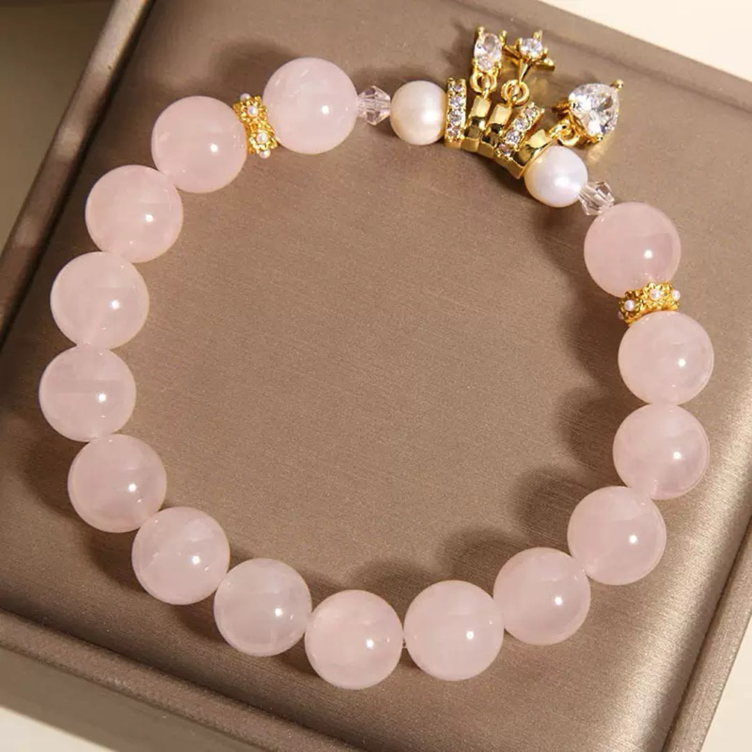 Bracelet élastique avec perles roses en quartz, perles blanches et un pendentif en forme de couronne ornée de zirconias et d'une perle nacrée.