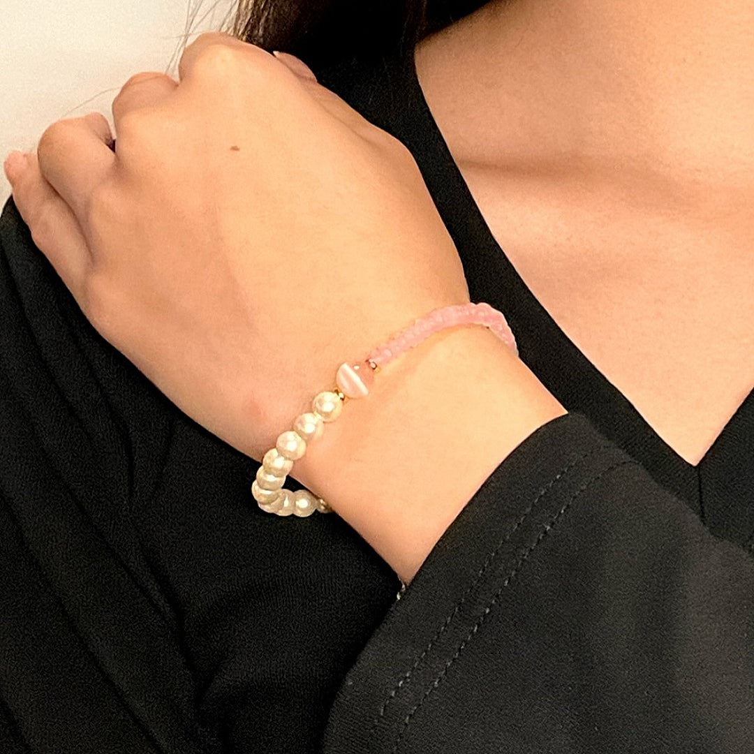 Bracelet en quartz rose et perles de culture, porté au poignet d'une femme, le bijou est composé de perles blanches rondes et de perles roses facettées.