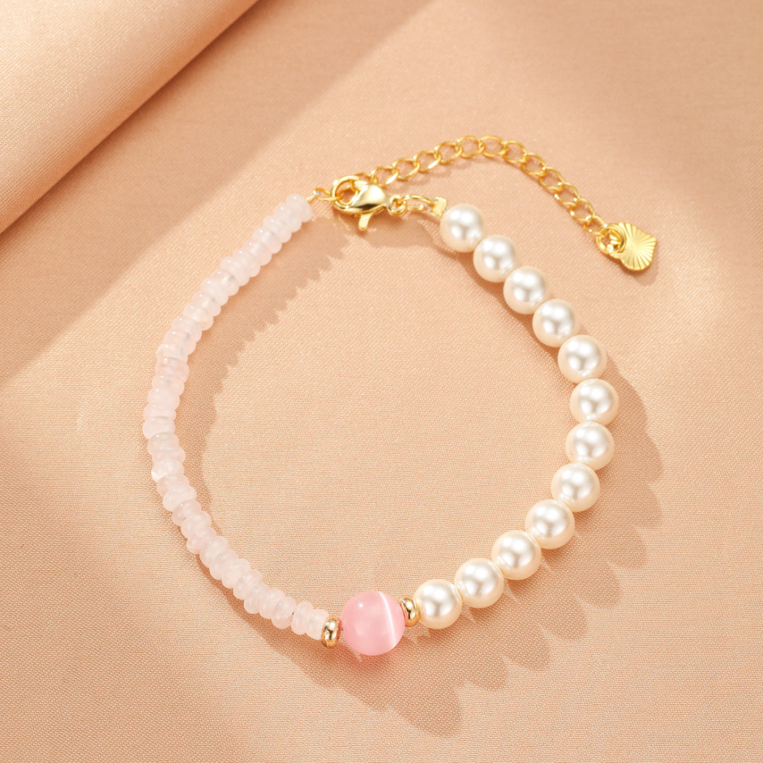 Bracelet élégant en quartz rose et perles nacrées avec une perle rose centrale et un fermoir doré, sur fond satiné.