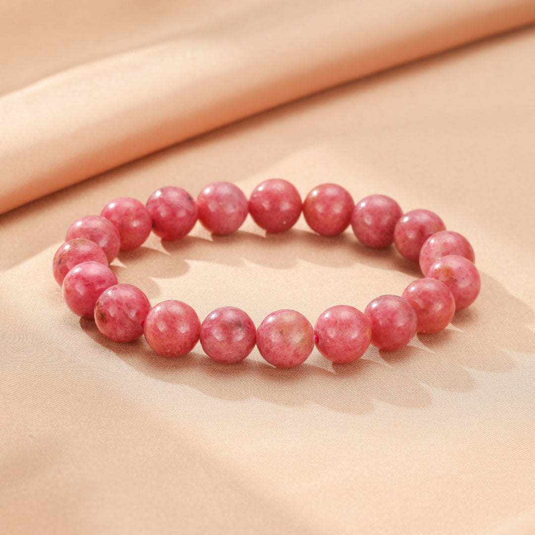 Bracelet en rhodonite rose perles rondes sur fond beige doux