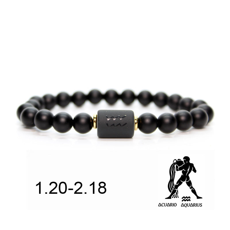 Bracelet en onyx noir avec un pendentif cylindrique noir gravé du symbole du Verseau et des perles dorées. Le bracelet est associé à la période du 20 janvier au 18 février, représentant le signe astrologique du Verseau.
