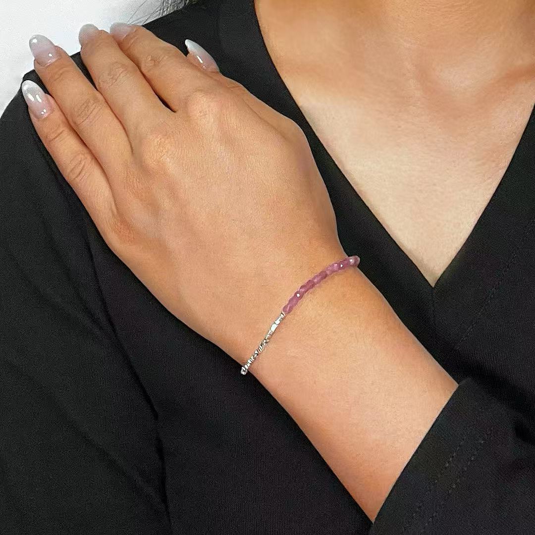 Bracelet fin en tourmaline rose intuitive sur un poignet féminin, avec une chaîne en argent martelé.