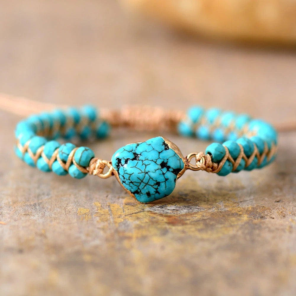 Bracelet en argent plaqué or avec une pierre turquoise brute au centre et des petites perles turquoise sur un fil beige.
