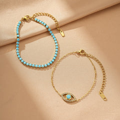 Deux bracelets dorés : un tennis en turquoise et un avec un pendentif œil stylisé serti de diamants et d'une turquoise centrale.