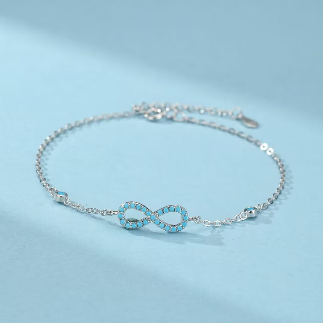 Bracelet infini en argent 925 orné de petites pierres turquoise bleues sur une chaîne délicate.