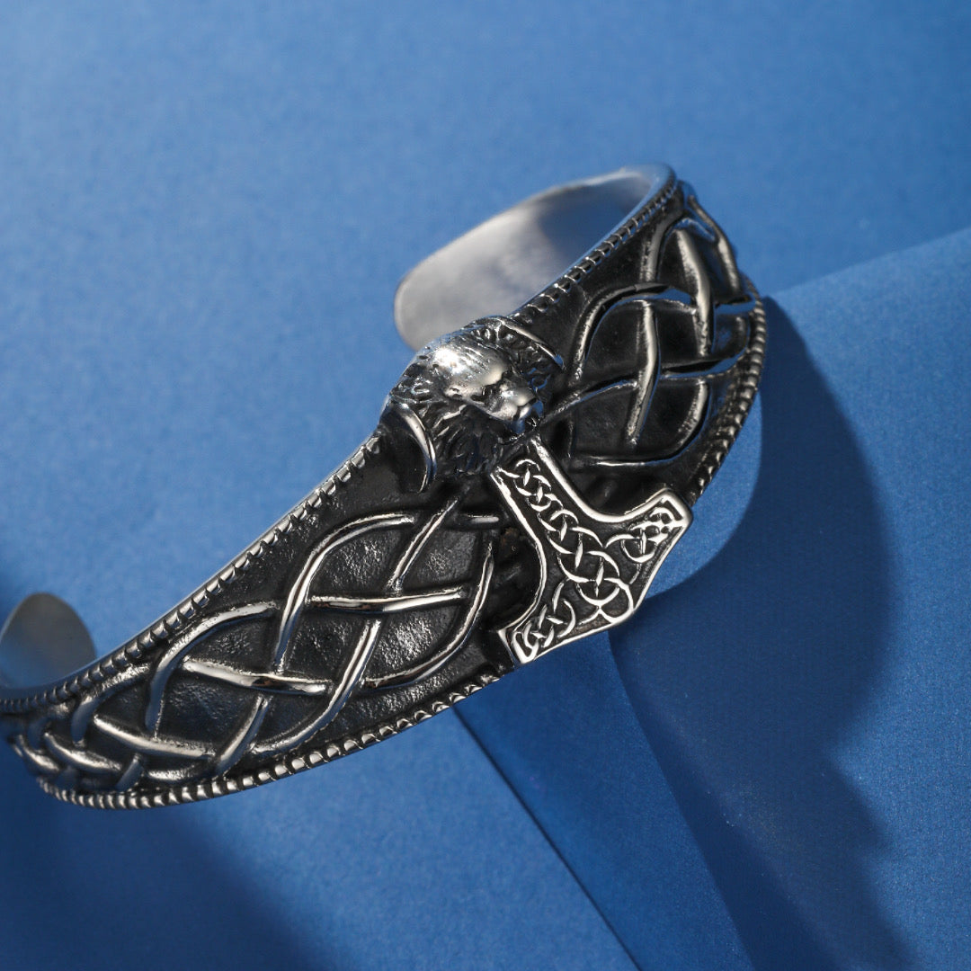 Bracelet jonc viking orné d'un marteau de Thor et d'une tête de loup stylisée, avec des motifs celtiques entrelacés.