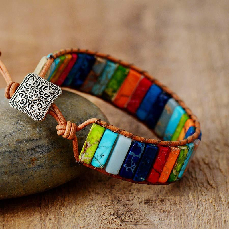 Bracelet jonc en cuir marron avec des pierres naturelles colorées représentant les 7 chakras et un fermoir carré argenté orné.