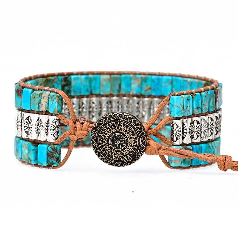 Bracelet jonc ethnique à plusieurs rangs de perles turquoise et argentées, noué avec un cordon en cuir marron et fermé par un fermoir rond gravé.