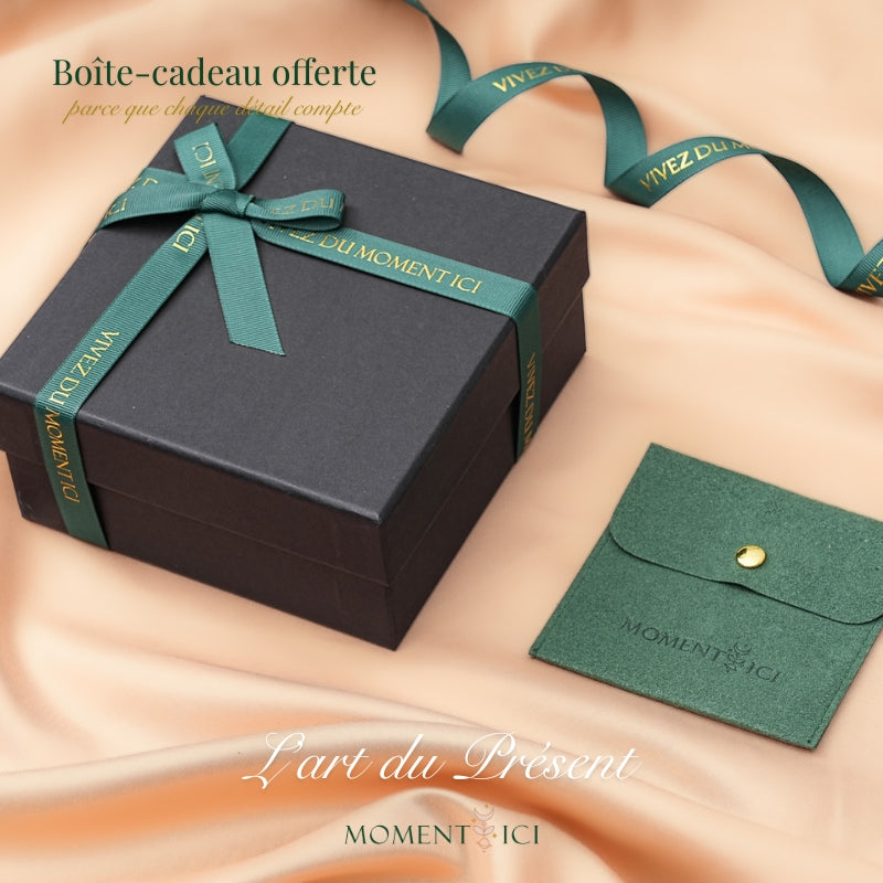 Boîte cadeau noire avec ruban vert "VIVEZ DU MOMENT ICI" et pochette verte "MOMENT ICI" sur fond satiné.
