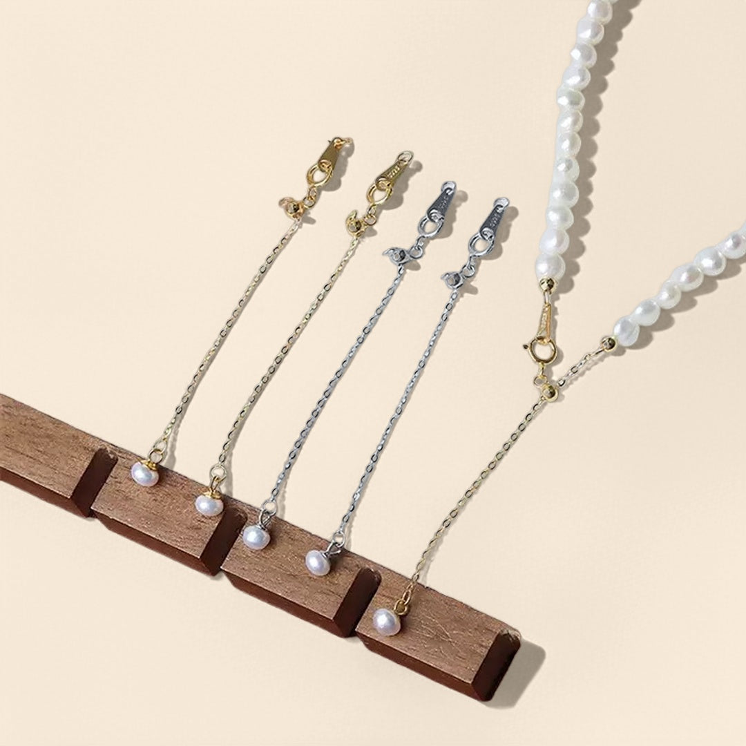 Chaînettes d'extension argentées et dorées avec perles, présentées sur un support en bois.