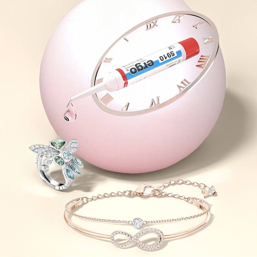 Une goutte de colle Ergo 5910 tombe d'un tube sur une bague en forme d'insecte et un bracelet infini en or rose ornés de diamants.