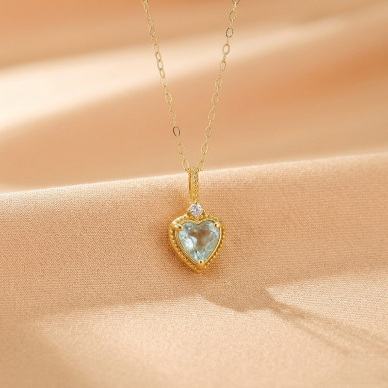 Collier "Amour Céleste" en argent plaqué or, avec un pendentif en forme de cœur d'aigue-marine bleu pâle et une petite pierre d'accent blanche.