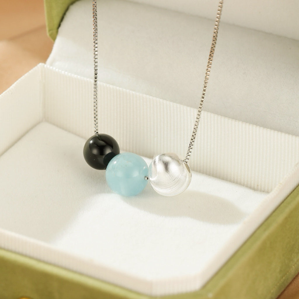 Collier Onde Lumineuse en Argent 925, orné d'une perle d'obsidienne noire, d'une perle d'aigue-marine bleu clair et d'une perle argentée texturée.