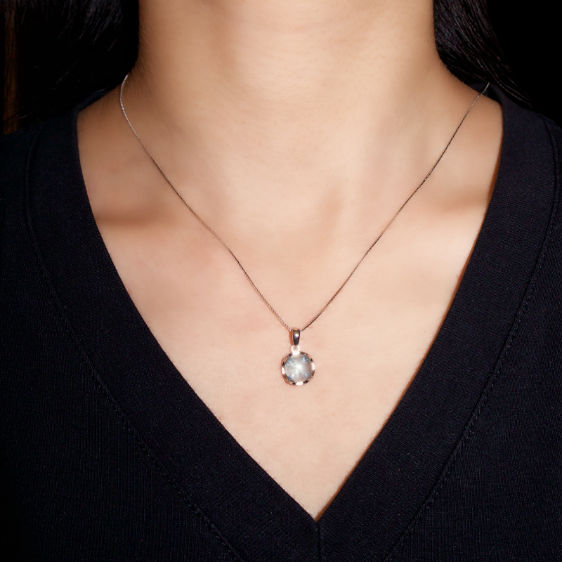 Collier avec pendentif rond en aigue-marine naturelle sur chaîne fine en argent 925, porté par une femme.