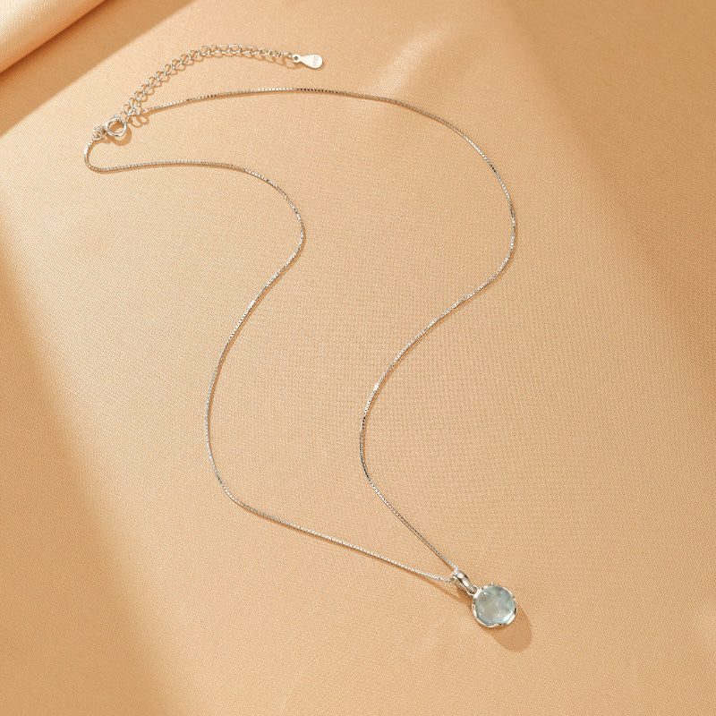 Collier en argent 925 avec un pendentif rond en aigue-marine bleu pâle, monté sur une fine chaîne type boîte.