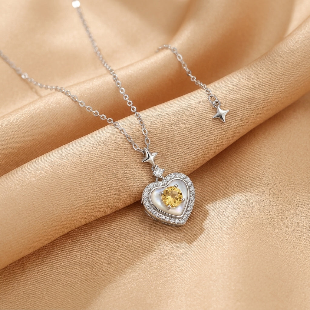 Collier en argent plaqué or 18 carats avec pendentif en forme de cœur orné d'une améthyste jaune, de zirconiums et de nacre, avec des étoiles décoratives.