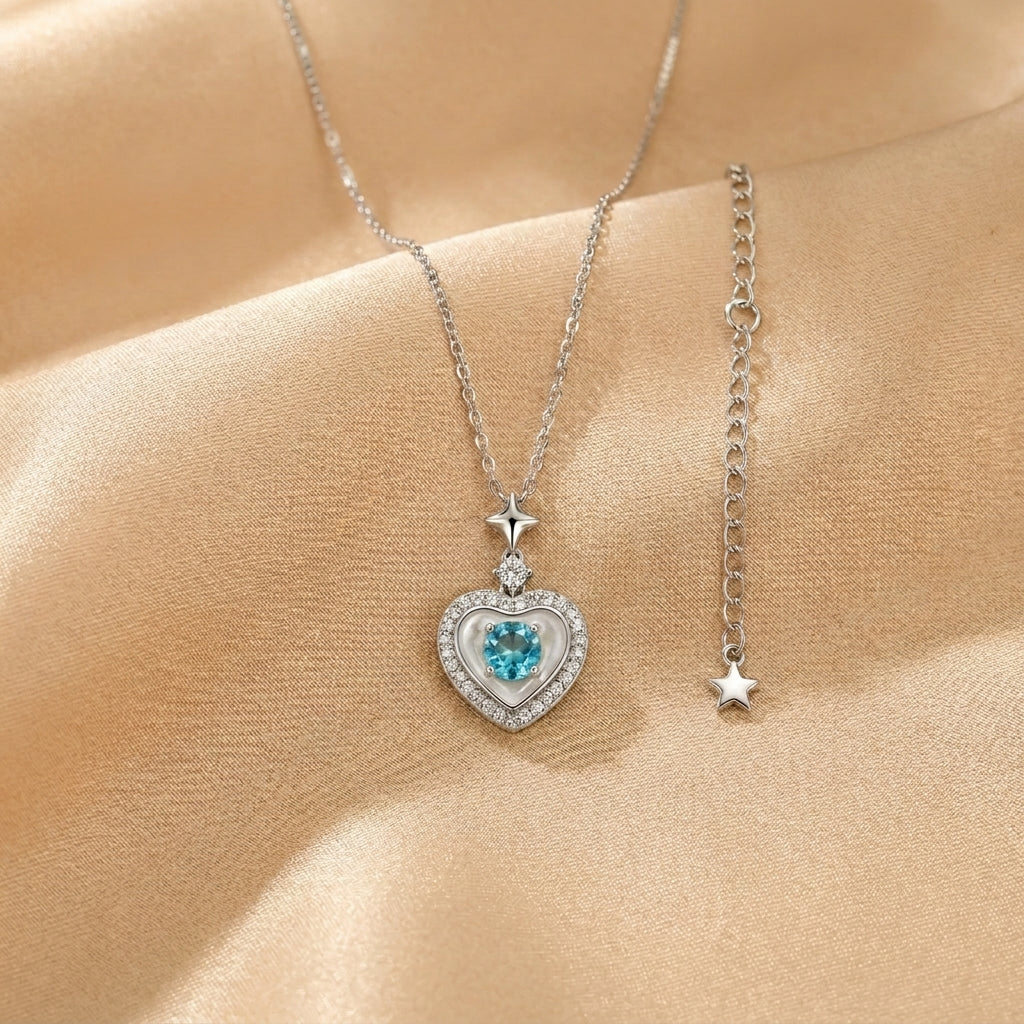 Collier cœur avec une pierre bleue au centre, entouré de petites pierres scintillantes, sur une chaîne en argent plaqué or 18K.
