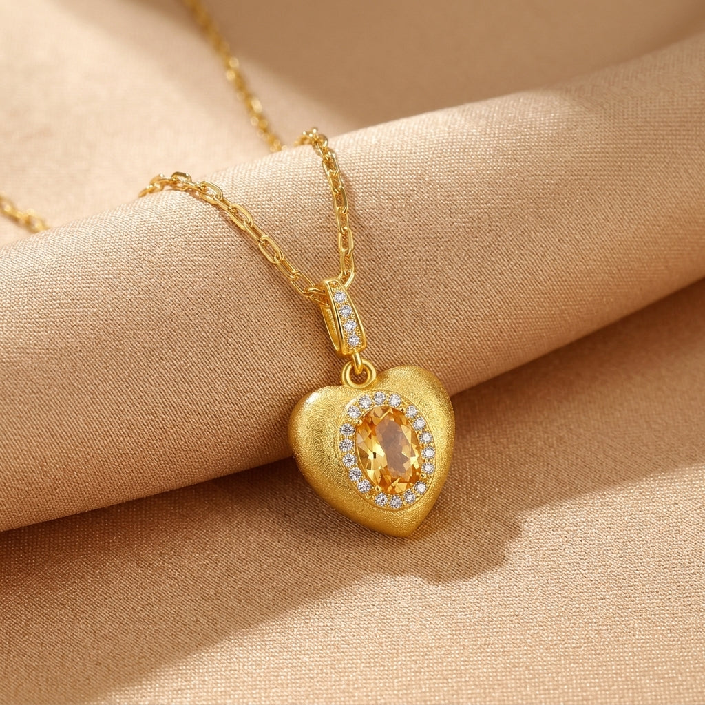 Collier cœur plaqué or avec citrine centrale ovale et diamants, sur fond satiné beige.