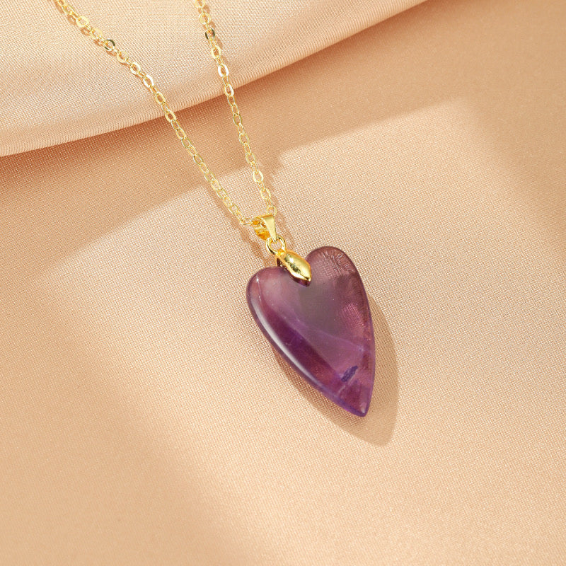 Collier doré à chaîne fine avec un pendentif en forme de cœur en améthyste violette translucide.