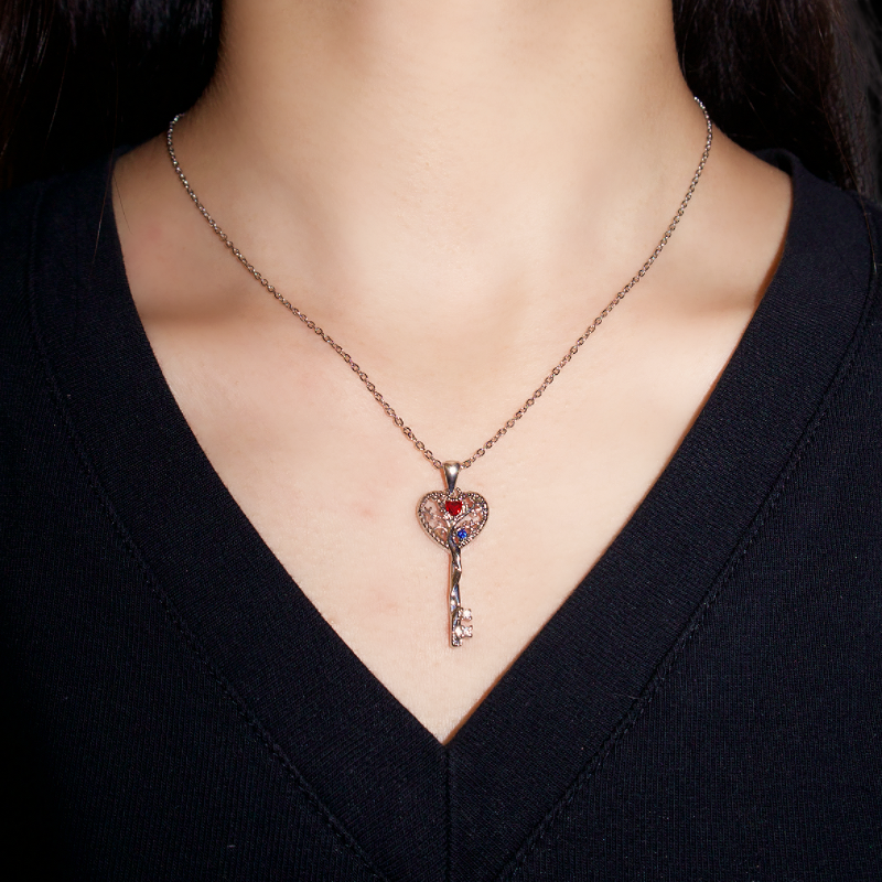 Collier Arbre de Vie avec pendentif en forme de clé orné de cristaux rouges et bleus, sur une chaîne en argent.
