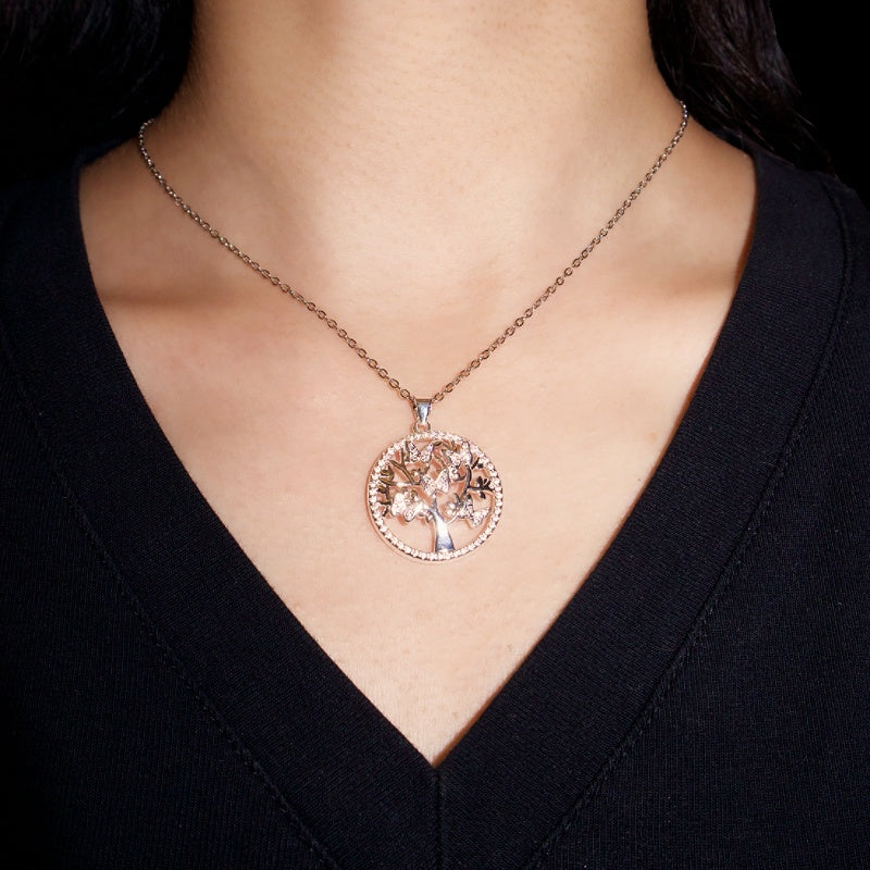 Collier Arbre de Vie en argent avec pendentif rond orné de cristaux et d'un arbre stylisé, porté par une femme sur fond noir.