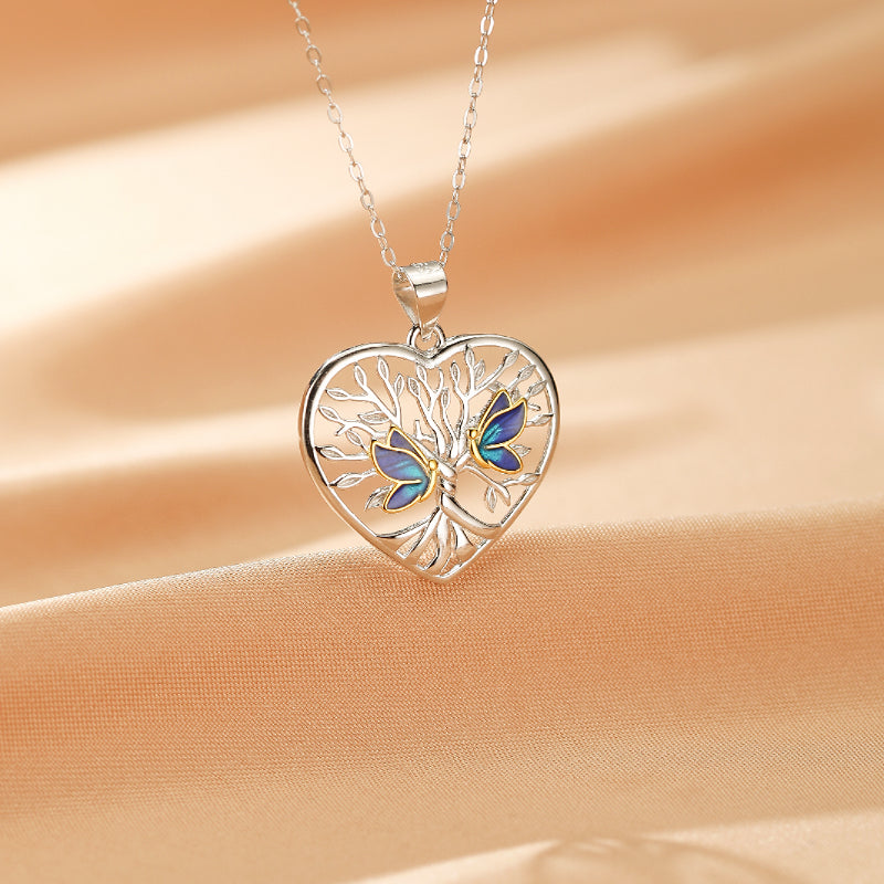Collier en argent 925 avec pendentif en forme de cœur représentant un arbre de vie orné de deux papillons bleus et verts.