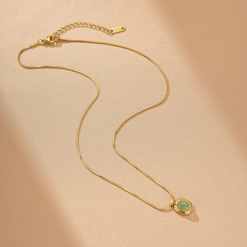 Collier doré à maille serpent avec un pendentif ovale en pierre d'aventurine verte, marque K18 gravée sur la chaîne.