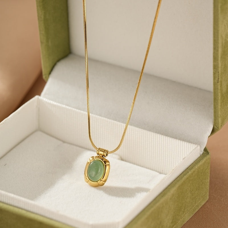 Collier en or avec pendentif ovale en aventurine verte, présenté dans une boîte cadeau verte.