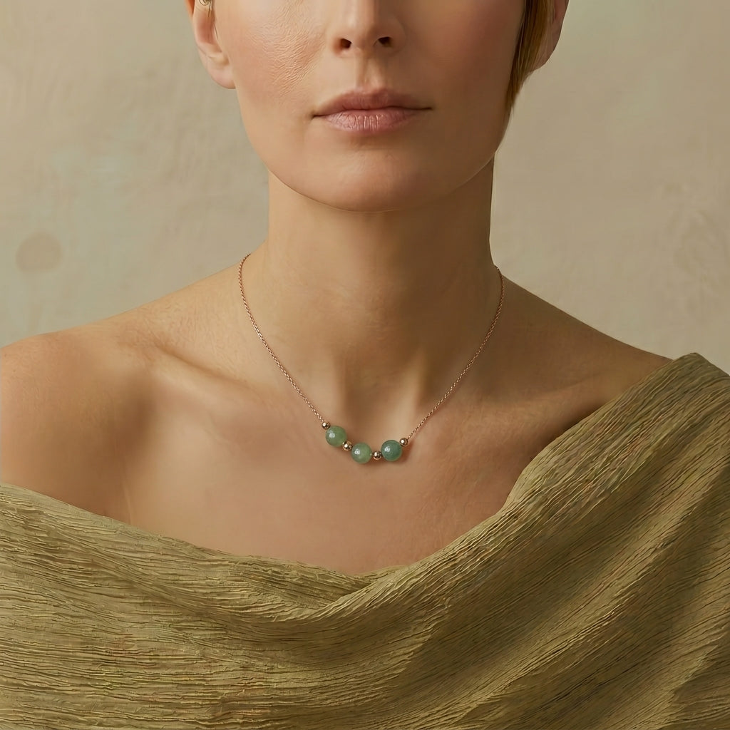 Collier en aventurine verte avec des perles rondes sur un décolleté, monté sur une chaîne dorée.