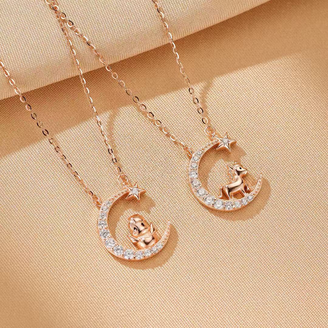 Deux colliers en argent plaqué or rose ornés de lunes serties de cristaux et d'étoiles, avec des pendentifs d'animaux (cheval et coq) assis sur la lune.