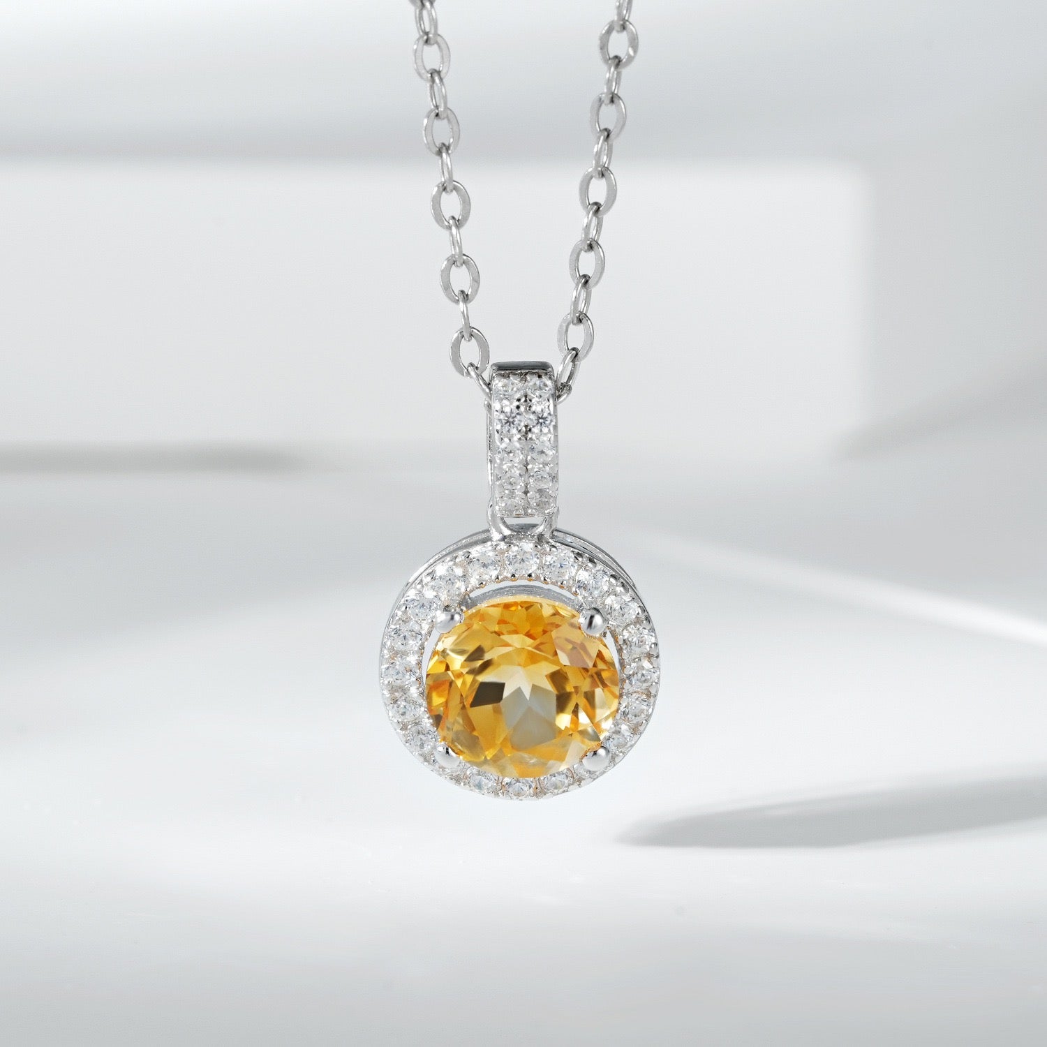 Collier en argent 925 avec une citrine ronde entourée de petits zircons cubiques, créant un halo scintillant.