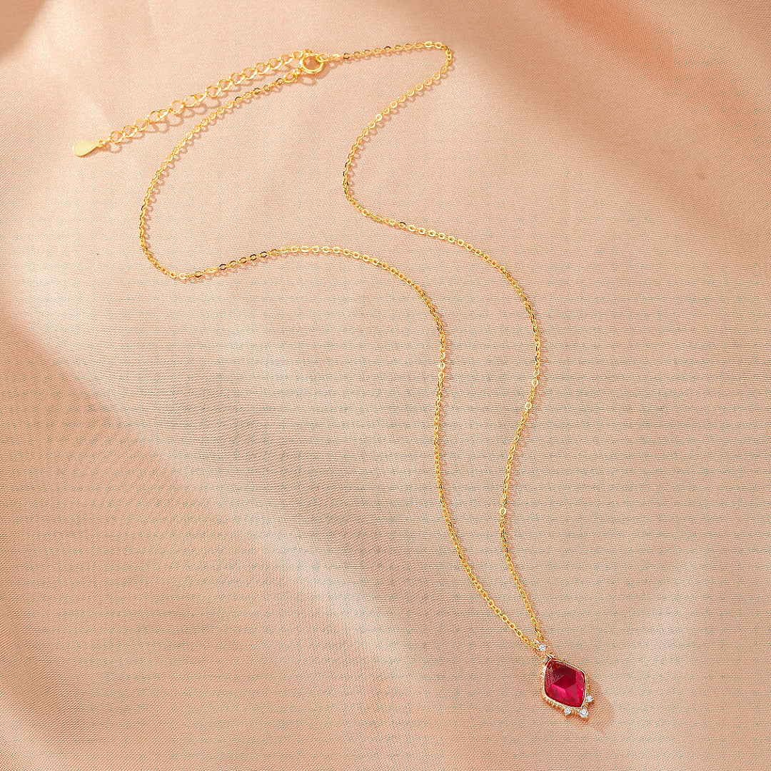Collier "Élixir de Grâce" en argent plaqué or, avec une pierre de cornaline rouge et de petites perles blanches serties sur un pendentif facetté en forme de losange.